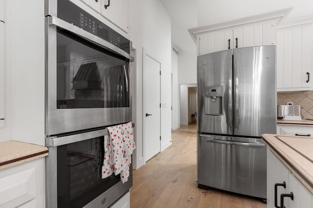 295 N Lakeshore Dr, Holland, MI 49424 - kitchen with appliances with stainless steel finishes, white cabinets, decorative backsplash, light countertops, and light wood-type flooring