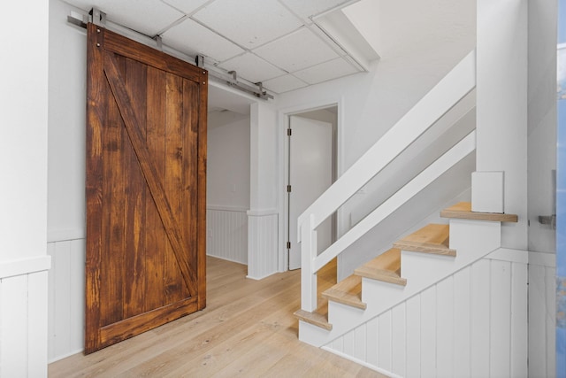 295 N Lakeshore Dr, Holland, MI 49424 - stairs with a barn door, a wainscoted wall, a paneled ceiling, and wood finished floors