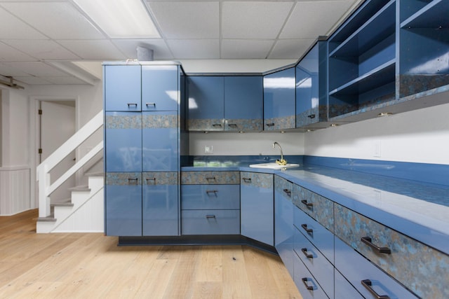 295 N Lakeshore Dr, Holland, MI 49424 - kitchen featuring a drop ceiling, light wood-style flooring, dark countertops, blue cabinetry, and open shelves