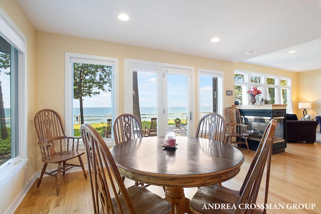1228 Shore Crest Dr, South Haven, MI 49090 - dining room featuring healthy amount of natural light, light wood-style flooring, a water view, recessed lighting, and a multi sided fireplace