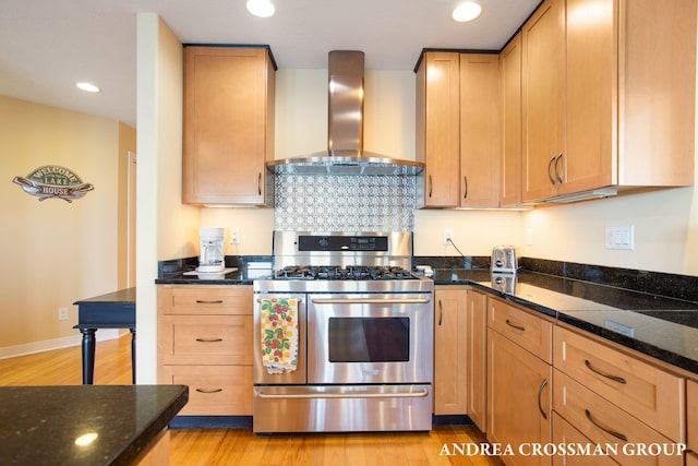 1228 Shore Crest Dr, South Haven, MI 49090 - kitchen with stainless steel gas stove, wall chimney exhaust hood, light wood-style floors, dark stone countertops, and recessed lighting