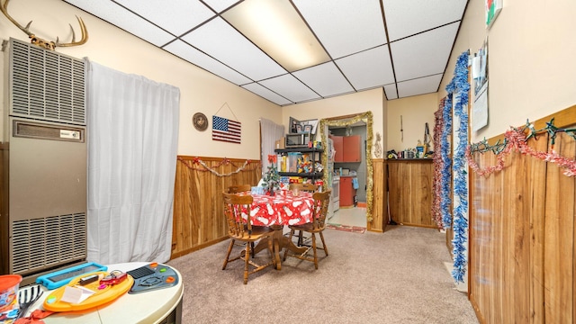 405 5th St, Evart, MI 49631 - carpeted dining space with a paneled ceiling, a wainscoted wall, a heating unit, and wooden walls