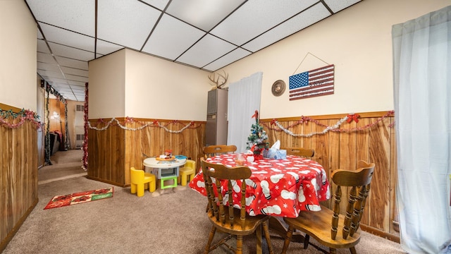 405 5th St, Evart, MI 49631 - carpeted dining space featuring wooden walls, a paneled ceiling, and a wainscoted wall