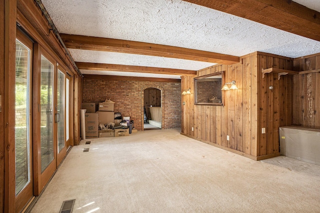 55835 Davis Ln, Dowagiac, MI 49047 - empty room featuring arched walkways, beam ceiling, carpet floors, wooden walls, and a textured ceiling