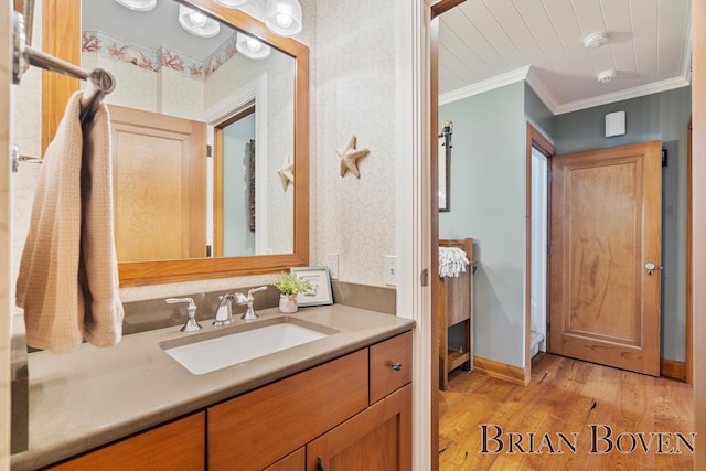 2625 Elmwood Dr, Pierson, MI 49339 - bathroom featuring vanity, wood finished floors, crown molding, and wallpapered walls