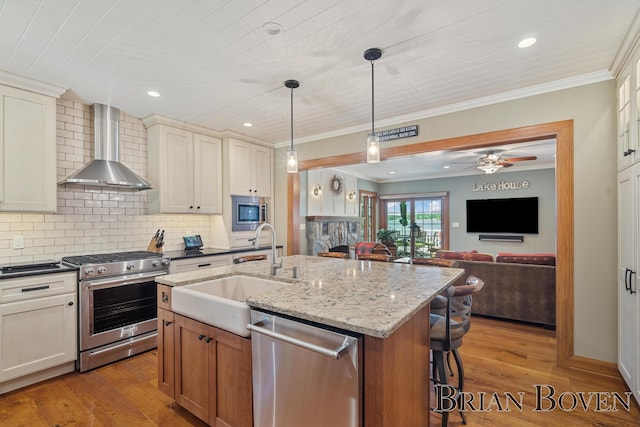 2625 Elmwood Dr, Pierson, MI 49339 - kitchen featuring stainless steel appliances, wall chimney exhaust hood, crown molding, backsplash, and a kitchen breakfast bar