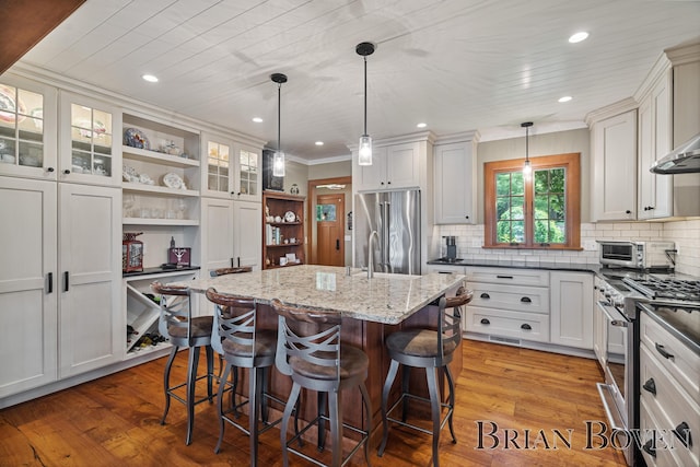 2625 Elmwood Dr, Pierson, MI 49339 - kitchen featuring stainless steel appliances, open shelves, a breakfast bar area, hardwood / wood-style floors, and ornamental molding