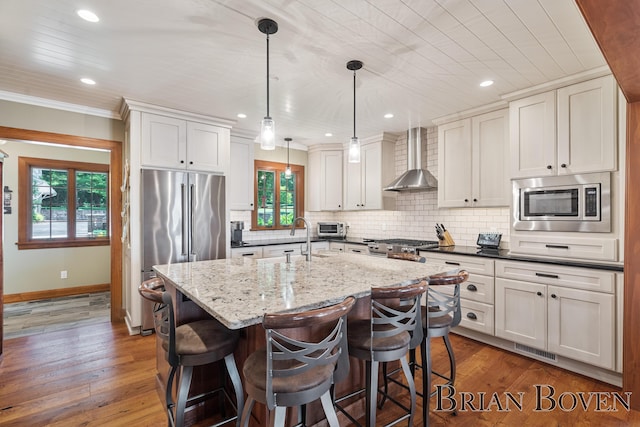 2625 Elmwood Dr, Pierson, MI 49339 - kitchen featuring appliances with stainless steel finishes, wall chimney exhaust hood, plenty of natural light, a breakfast bar, and recessed lighting