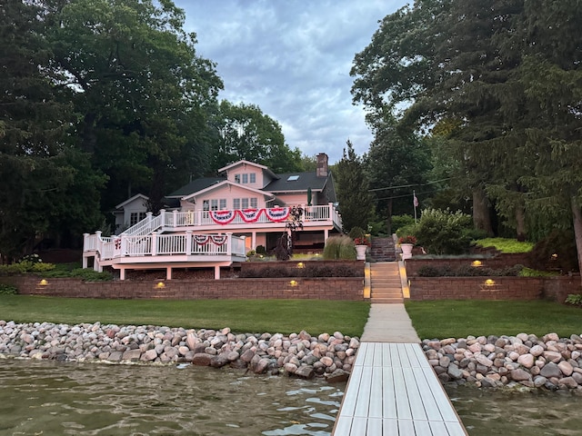 2625 Elmwood Dr, Pierson, MI 49339 - rear view of house with a chimney, a lawn, and a deck with water view