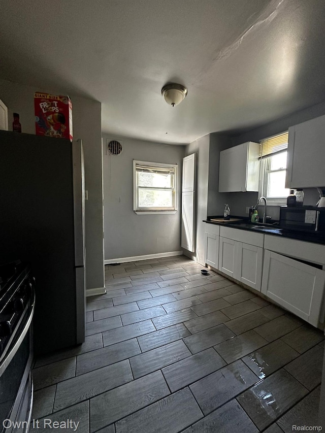 16595 Griggs St, Detroit, MI 48221 - kitchen featuring stainless steel range oven, dark countertops, healthy amount of natural light, and white cabinets