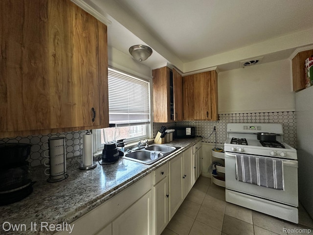 19505 Sunderland Rd, Detroit, MI 48219 - kitchen featuring white gas range oven, tile patterned flooring, white cabinets, and backsplash