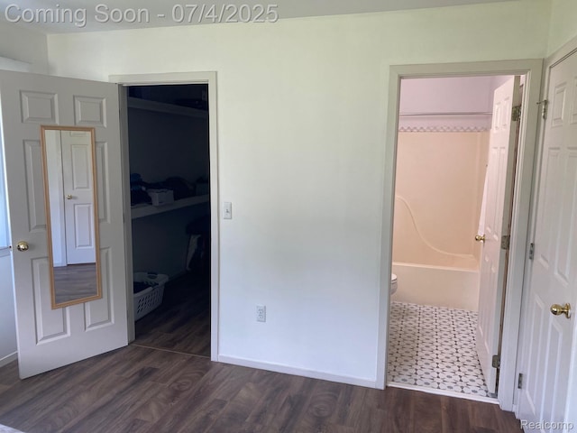 1093 Lake Park Cir Unit 6, Grand Blanc, MI 48439 - unfurnished bedroom with dark wood-type flooring, connected bathroom, and a walk in closet