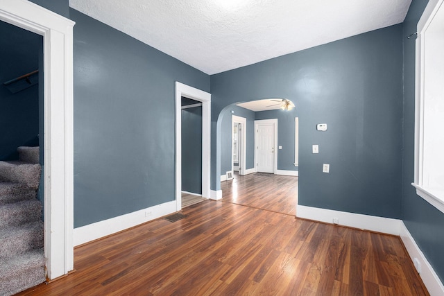 863 Burton St SE, Grand Rapids, MI 49507 - empty room featuring arched walkways, wood finished floors, stairway, and a textured ceiling