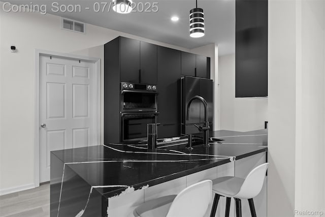 8461 Towne Center Cir N, Warren, MI 48093 - kitchen with dark cabinetry, black appliances, dark countertops, pendant lighting, and a breakfast bar
