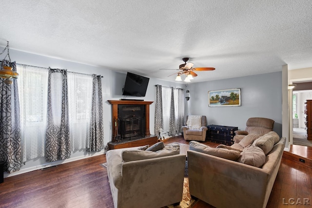 15858 Lelah Ln, Addison, MI 49220 - living room featuring a textured ceiling, a ceiling fan, dark wood-type flooring, and a glass covered fireplace