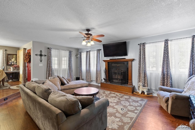15858 Lelah Ln, Addison, MI 49220 - living area with ceiling fan, a glass covered fireplace, a textured ceiling, and wood finished floors
