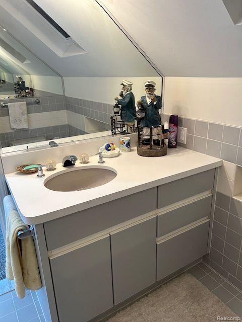 32241 N River Rd, Harrison Township, MI 48045 - bathroom with tile patterned floors, vanity, tile walls, and a skylight