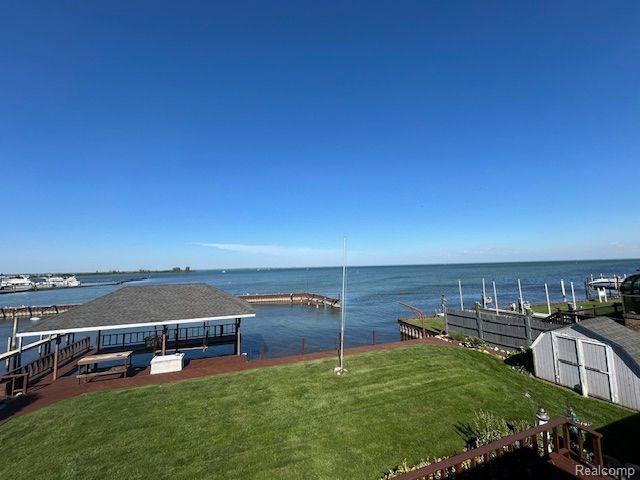 32241 N River Rd, Harrison Township, MI 48045 - view of grassy yard with a dock, a water view, and a storage shed
