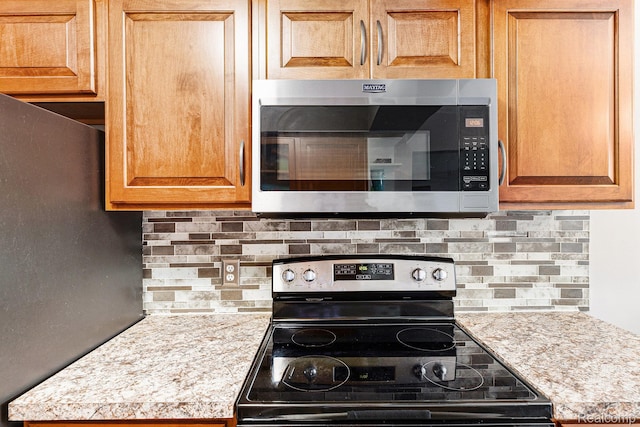 8150 24 Mile Rd, Shelby Twp, MI 48316 - kitchen featuring stainless steel microwave, range with electric cooktop, freestanding refrigerator, and tasteful backsplash