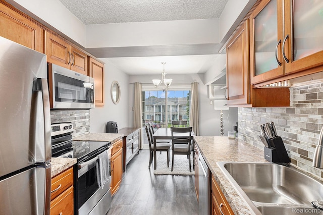 8150 24 Mile Rd, Shelby Twp, MI 48316 - kitchen featuring appliances with stainless steel finishes, brown cabinetry, a chandelier, wood finished floors, and a textured ceiling