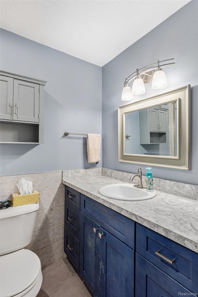 8150 24 Mile Rd, Shelby Twp, MI 48316 - bathroom with tile walls, vanity, tile patterned flooring, a wainscoted wall, and a textured ceiling