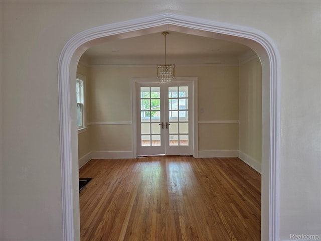 2681 Burlingame St, Detroit, MI 48206 - empty room with wood finished floors, arched walkways, french doors, and a chandelier