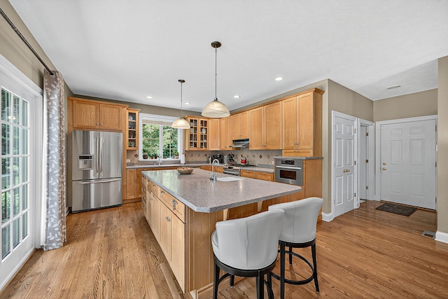 29750 Edwards Way, Niles, MI 49120 - kitchen featuring appliances with stainless steel finishes, a center island with sink, light wood-style flooring, glass insert cabinets, and recessed lighting