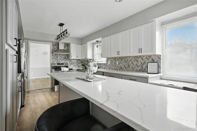 22679 Bell Brook St, Southfield, MI 48034 - kitchen with stainless steel appliances, wall chimney exhaust hood, tasteful backsplash, light stone countertops, and light wood-style floors