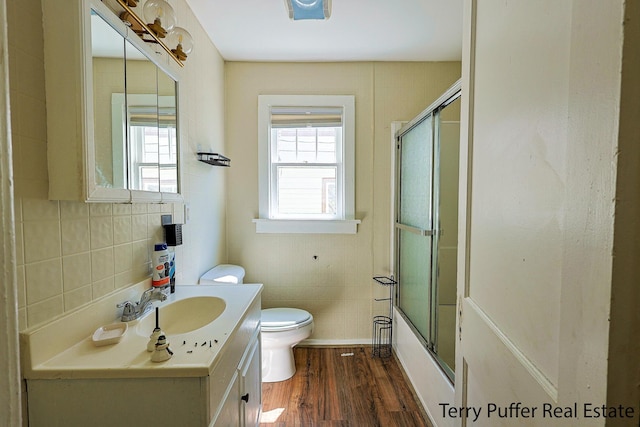 594 Oak Ave, Muskegon, MI 49442 - bathroom with wood finished floors, tile walls, vanity, and shower / bath combination with glass door