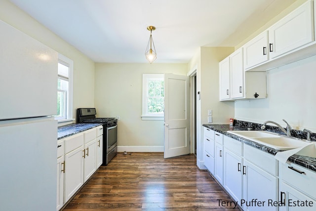 594 Oak Ave, Muskegon, MI 49442 - kitchen with freestanding refrigerator, stainless steel gas stove, dark wood-style flooring, and white cabinets