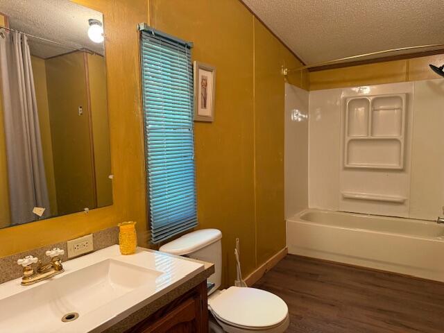 1422 E Monroe St, White Cloud, MI 49349 - full bath with vanity, wood finished floors, shower / bathtub combination with curtain, and a textured ceiling