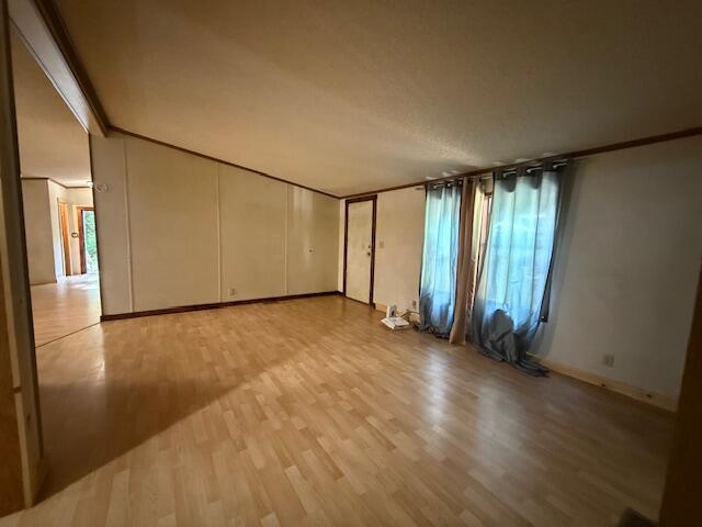 1422 E Monroe St, White Cloud, MI 49349 - empty room featuring light wood-style flooring and ornamental molding