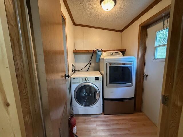 1422 E Monroe St, White Cloud, MI 49349 - laundry room featuring ornamental molding, wood finished floors, a textured ceiling, and washing machine and clothes dryer