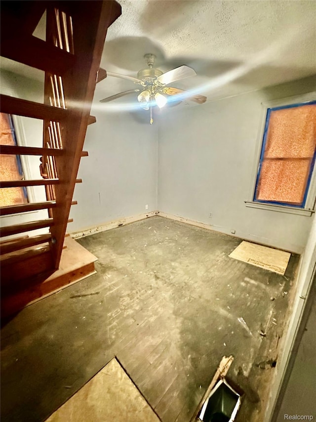 26735 Annapolis St, Dearborn Heights, MI 48125 - unfurnished living room with a ceiling fan, a textured ceiling, unfinished concrete floors, and stairs