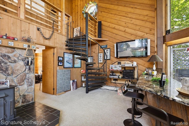 8641 Brettonwood Shores Rd, Rapid City, MI 49676 - carpeted living room featuring wooden walls, stairway, and a towering ceiling