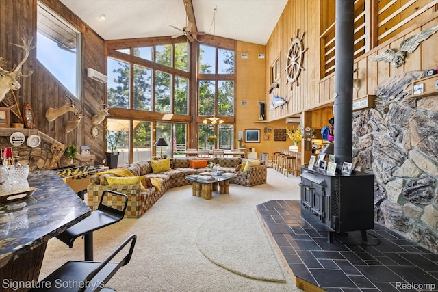 8641 Brettonwood Shores Rd, Rapid City, MI 49676 - living area featuring high vaulted ceiling, ceiling fan, a wood stove, beamed ceiling, and wood walls