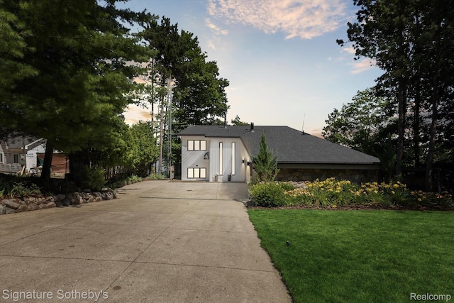8641 Brettonwood Shores Rd, Rapid City, MI 49676 - view of front of property featuring driveway, a front yard, stone siding, and roof with shingles