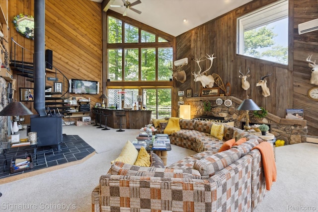 8641 Brettonwood Shores Rd, Rapid City, MI 49676 - living area with wood walls, carpet, a wood stove, healthy amount of natural light, and high vaulted ceiling