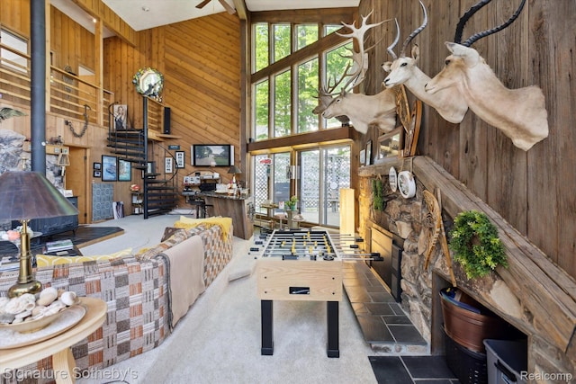 8641 Brettonwood Shores Rd, Rapid City, MI 49676 - living area with wood walls, plenty of natural light, a towering ceiling, carpet, and a wood stove