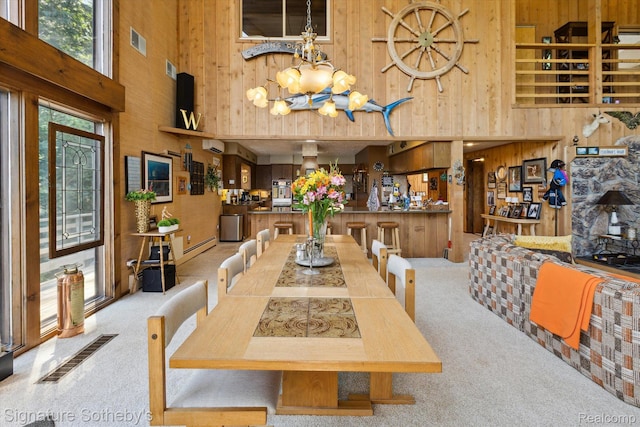 8641 Brettonwood Shores Rd, Rapid City, MI 49676 - carpeted dining area with a high ceiling, wood walls, plenty of natural light, and a chandelier