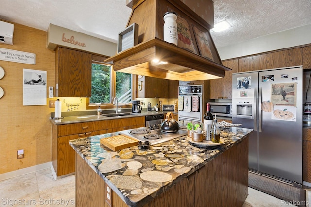 8641 Brettonwood Shores Rd, Rapid City, MI 49676 - kitchen with appliances with stainless steel finishes, a textured ceiling, a kitchen island, dark stone counters, and brown cabinets