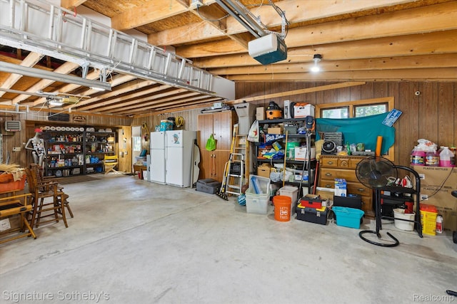 8641 Brettonwood Shores Rd, Rapid City, MI 49676 - garage featuring freestanding refrigerator, wooden walls, and a garage door opener