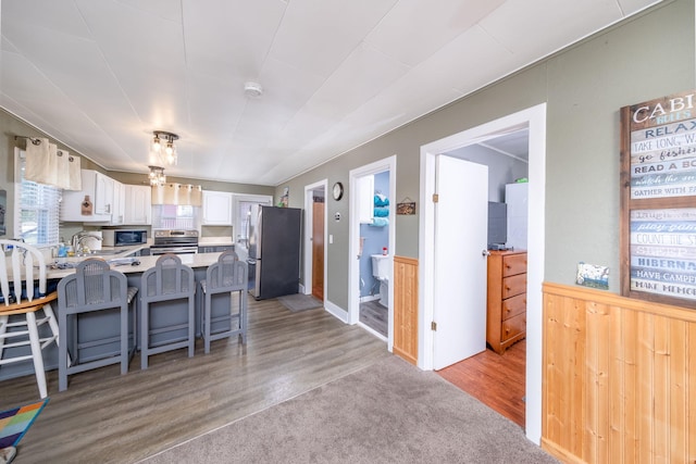 19336 E Chippewa Dr, Chippewa Lake, MI 49320 - kitchen with stainless steel appliances, white cabinets, a peninsula, light countertops, and a kitchen breakfast bar