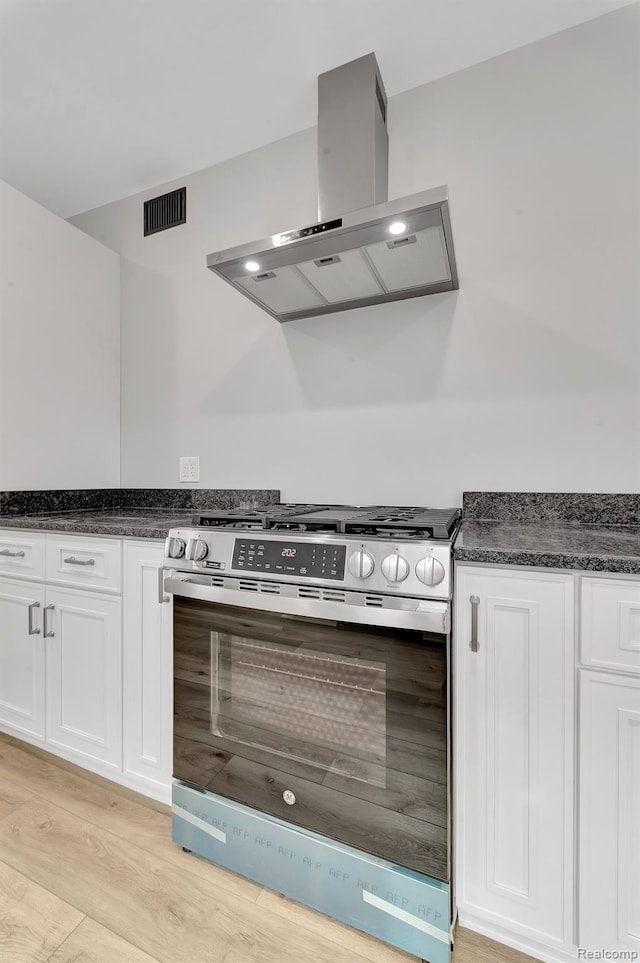 5291 Devonshire Rd, Detroit, MI 48224 - kitchen featuring stainless steel gas range oven, wall chimney range hood, white cabinets, and light wood-style floors