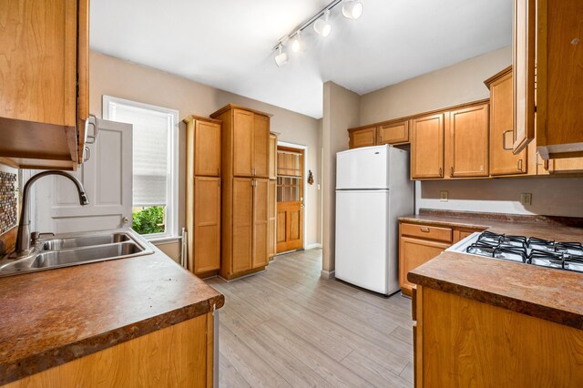 920 Wisconsin Ave, Saint Joseph, MI 49085 - kitchen featuring freestanding refrigerator, light wood-type flooring, brown cabinetry, dark countertops, and rail lighting