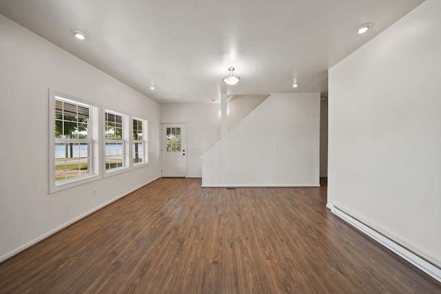 210 W Grove Ave, Michigan Center, MI 49254 - unfurnished living room with dark wood-style floors, a baseboard heating unit, recessed lighting, and lofted ceiling