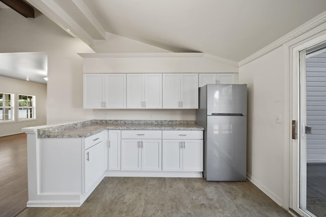 210 W Grove Ave, Michigan Center, MI 49254 - kitchen with freestanding refrigerator, lofted ceiling, a peninsula, white cabinetry, and light wood-style floors