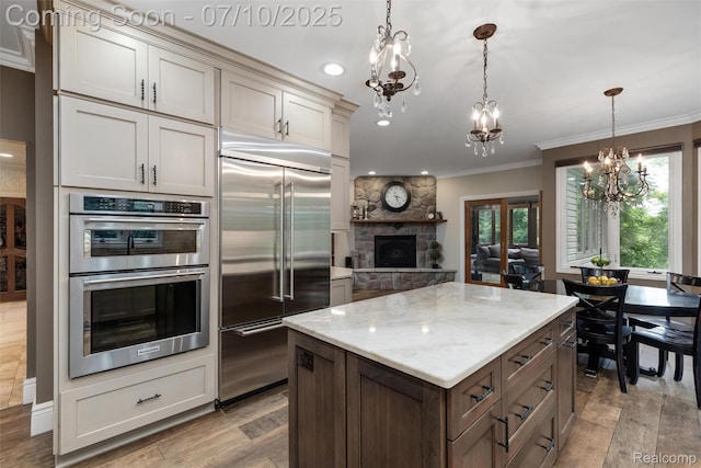 1444 W Clarkston Rd, Lake Orion, MI 48362 - kitchen featuring appliances with stainless steel finishes, a chandelier, ornamental molding, light wood finished floors, and light stone countertops