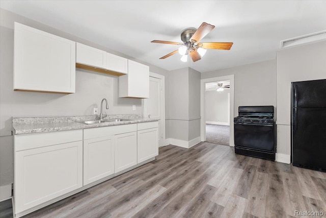 922 Maple, Wyandotte, MI 48192 - kitchen featuring black appliances, a ceiling fan, white cabinetry, light wood finished floors, and light stone countertops
