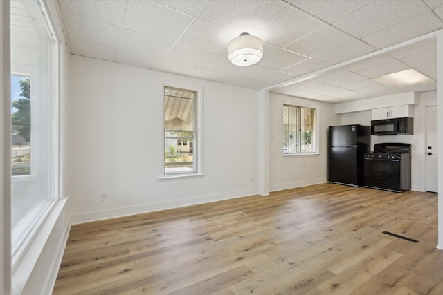 400 Burton St SW, Grand Rapids, MI 49507 - kitchen with black appliances, a paneled ceiling, white cabinets, and light wood-type flooring